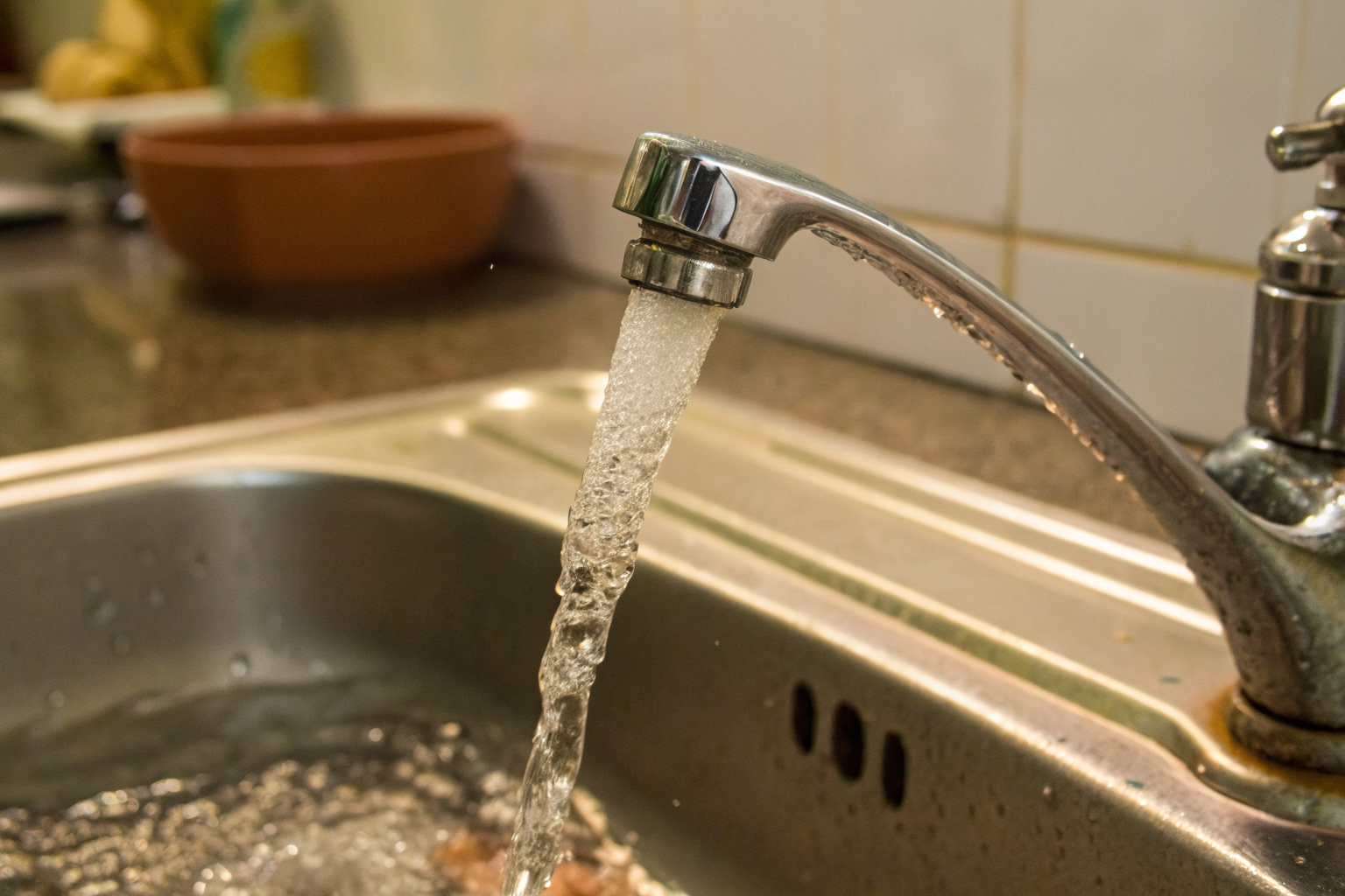 Tap with discolored, bubbly water in a kitchen sink.
