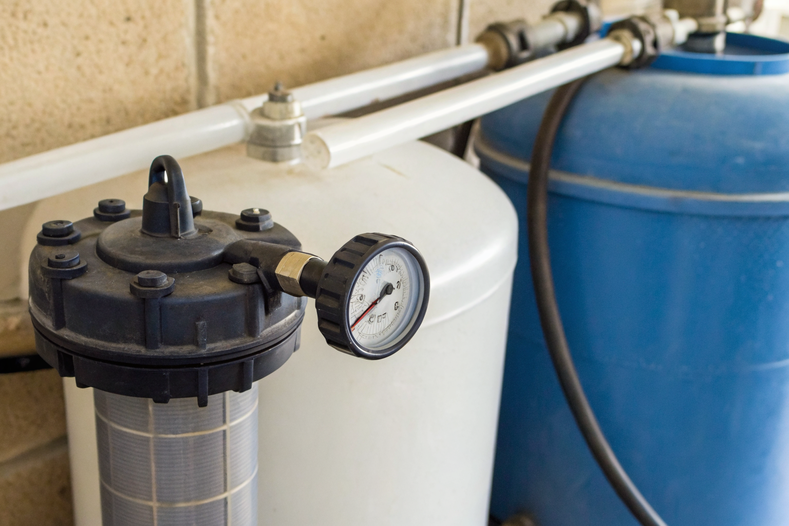 Water filter housing with pressure gauge over 15 PSI, showing fouling.